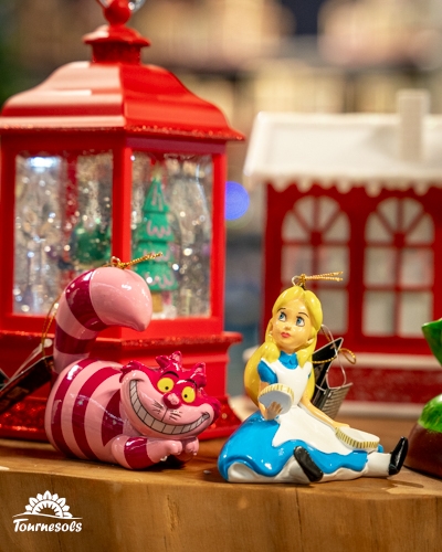 Ornements Disney avec Alice et le Chat de Cheshire devant des décorations de Noël.